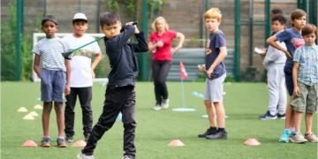 Young golfers practicing their skills while receiving guidance from a coach.