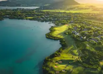 A golf course with a body of water and a hill in the background.