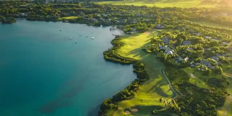 A golf course with a body of water and a hill in the background.