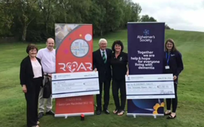 A group of people standing in front of a large cheque.
