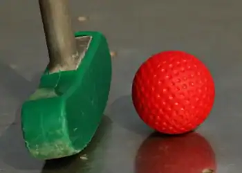 a green and red golf club and a red ball
