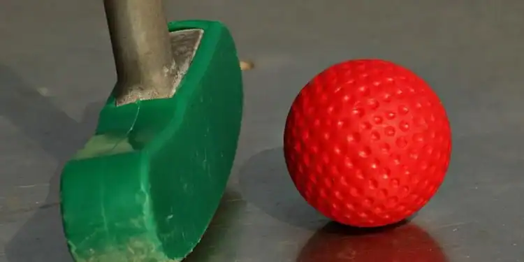 a green and red golf club and a red ball