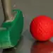 a green and red golf club and a red ball