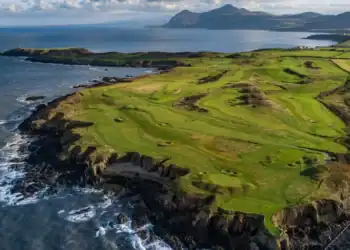 View of golfers on Nefyn Golf Club’s dramatic peninsula with the Irish Sea beyond.