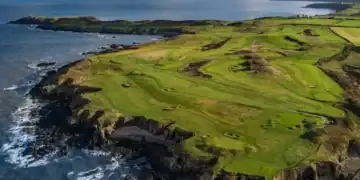 View of golfers on Nefyn Golf Club’s dramatic peninsula with the Irish Sea beyond.