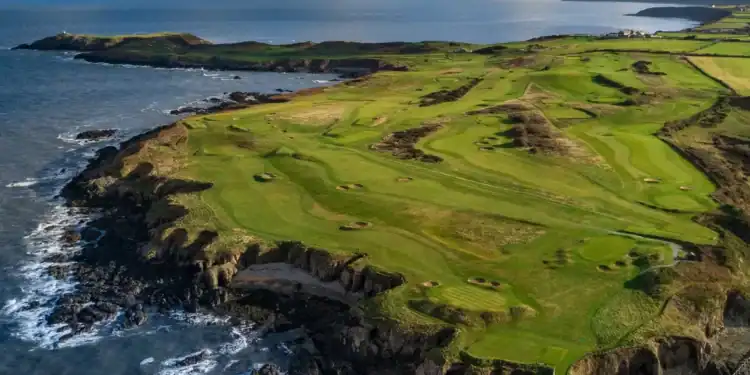 View of golfers on Nefyn Golf Club’s dramatic peninsula with the Irish Sea beyond.