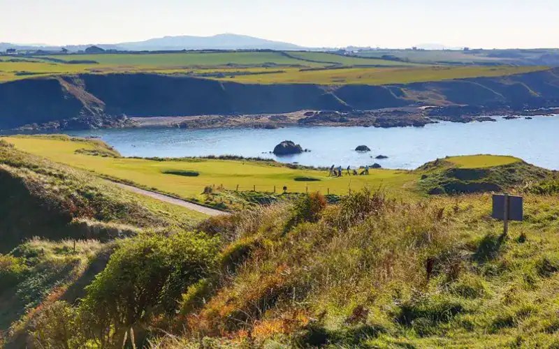View of golfers on Nefyn Golf Club’s dramatic peninsula.