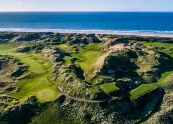 A golf course with the sea and beach in the background.