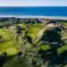 A golf course with the sea and beach in the background.