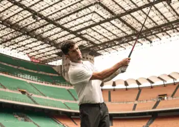 Christian Pulisic holding a golf club in a stadium.