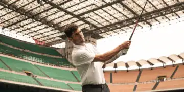 Christian Pulisic holding a golf club in a stadium.