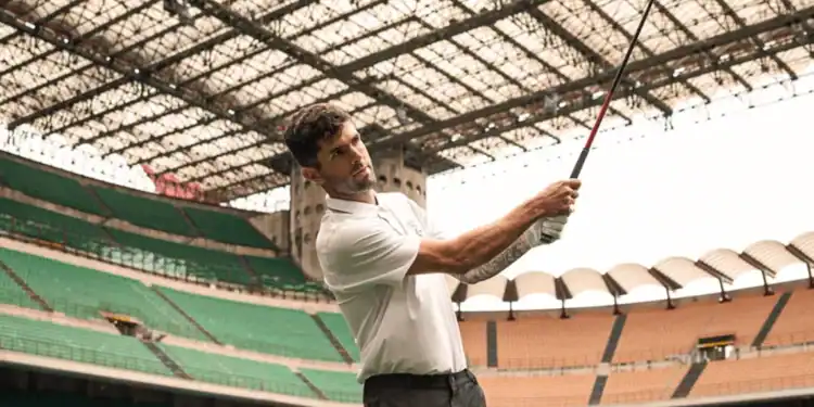 Christian Pulisic holding a golf club in a stadium.