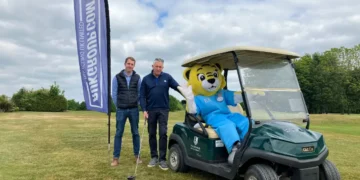 a man standing next to a person in a golf cart