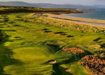 a golf course with sand bunkers and a beach