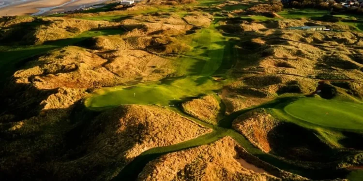 a golf course with sand dunes and water in the background