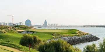 a golf course with water and city in the background
