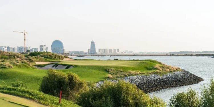 a golf course with water and city in the background