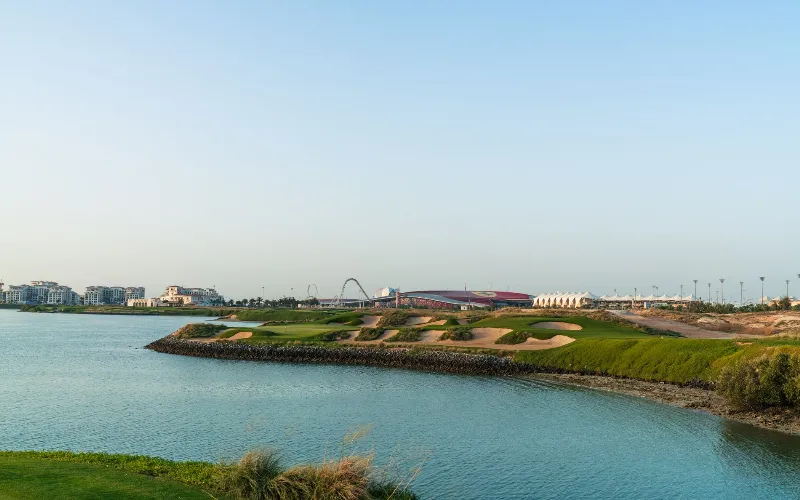 A golf course with a body of water and a building.