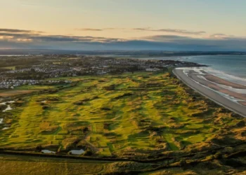 a golf course with a beach and water in the background