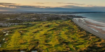 a golf course with a beach and water in the background