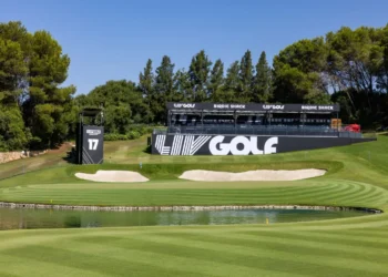 a golf course with a pond and a large black sign