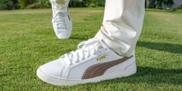 a person's feet in white shoes on grass