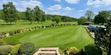 a large green lawn with cars parked in the back