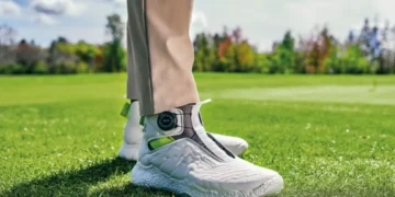 Stylish golf shoes on green grass.