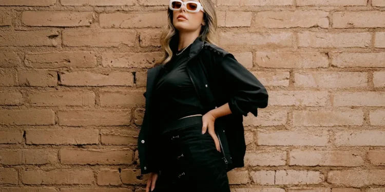 Stylish woman against textured brick wall.