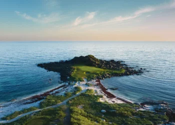 Golf course surrounded by serene waters.