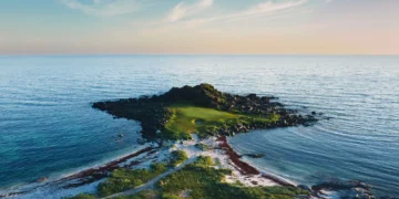 Golf course surrounded by serene waters.