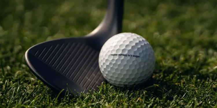 Golf ball and club on grass.