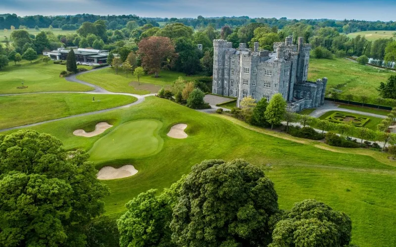 Lush golf course beside historic castle.