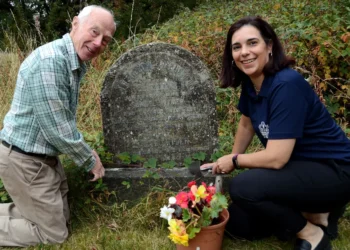 Two people tending to a gravestone.