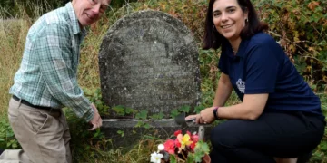 Two people tending to a gravestone.