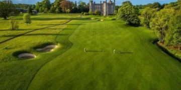 Golfers on lush green course, castle backdrop