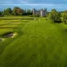 Golfers on lush green course, castle backdrop