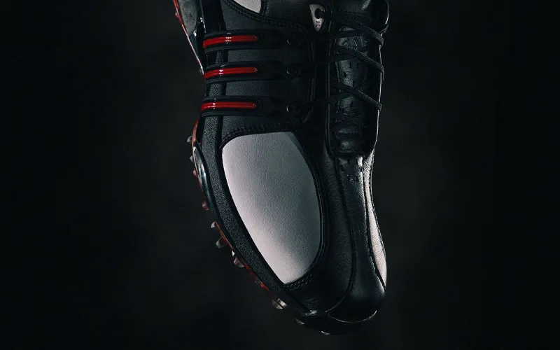 Stylish black golf shoe with red accents.